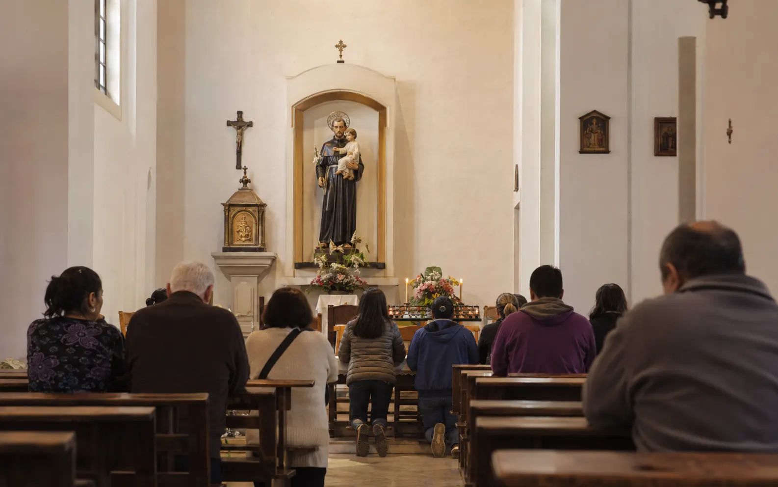 Grupo de personas rezando a San Cayetano en una iglesia