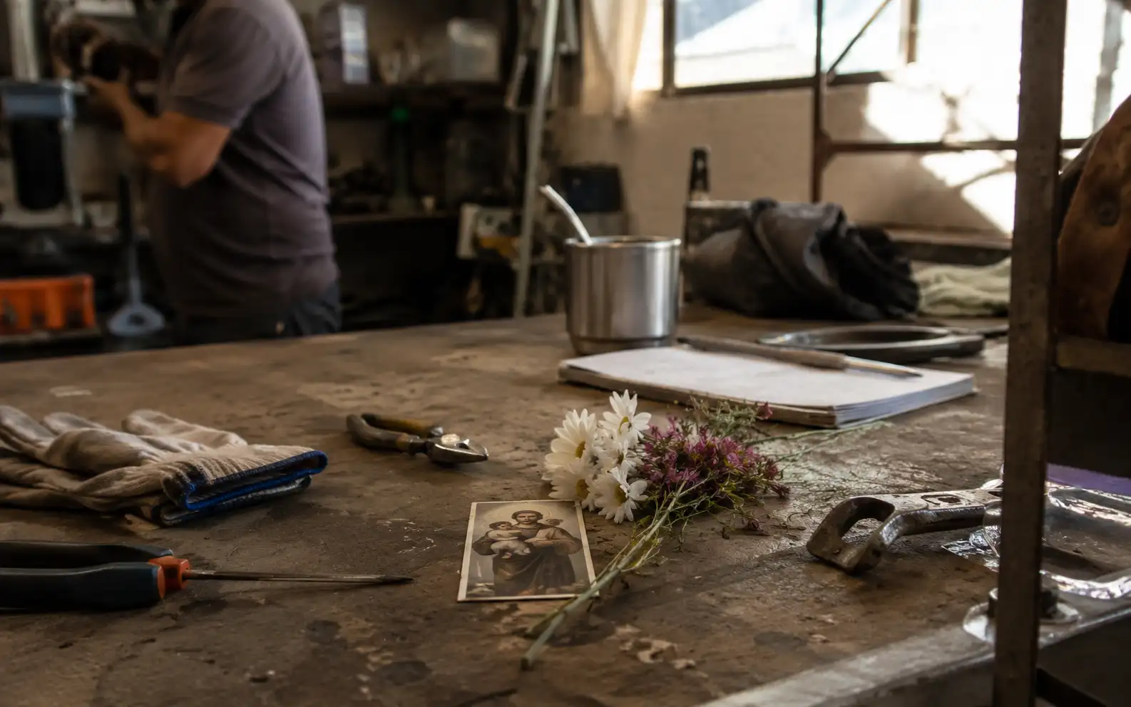 Mesa de trabajo con herramientas, flores y una estampita de San Cayetano